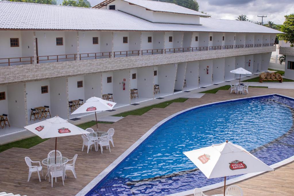 Paraiso Barra Hotel في بارا دي سانتو أنطونيو: اطلالة علوية على فندق به مسبح وطاولات ومظلات