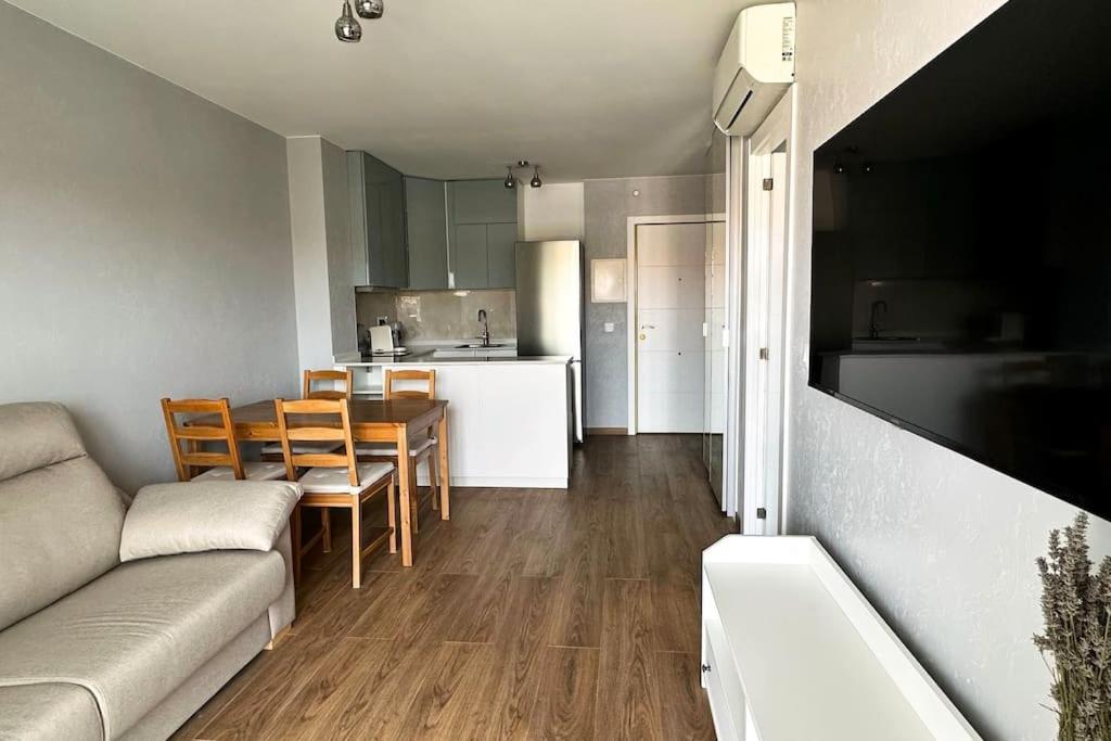 ein Wohnzimmer und eine Küche mit einem Sofa und einem Tisch in der Unterkunft Apartamento acogedor , Blanes in Blanes