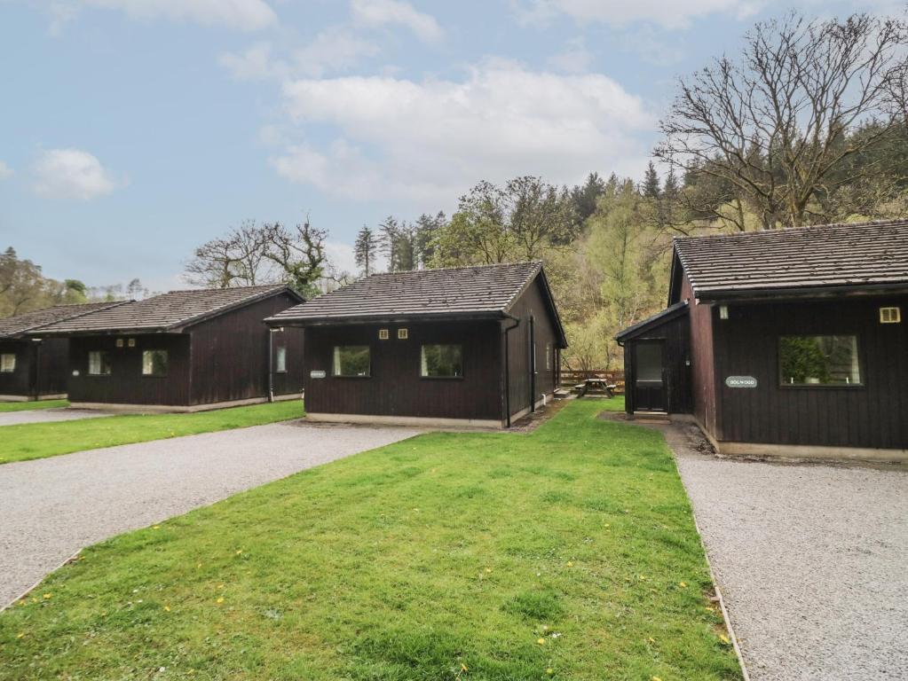 a group of three buildings with a grass yard at Chestnut Timber Lodge in Keswick