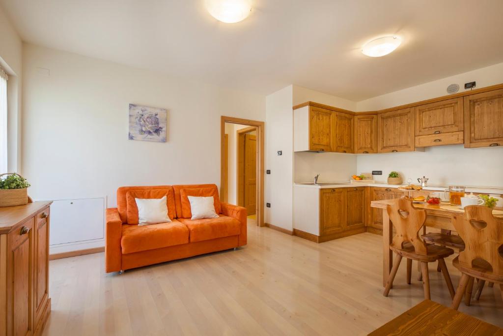 an orange couch in a kitchen with a table at Residenza Casale in Comano Terme