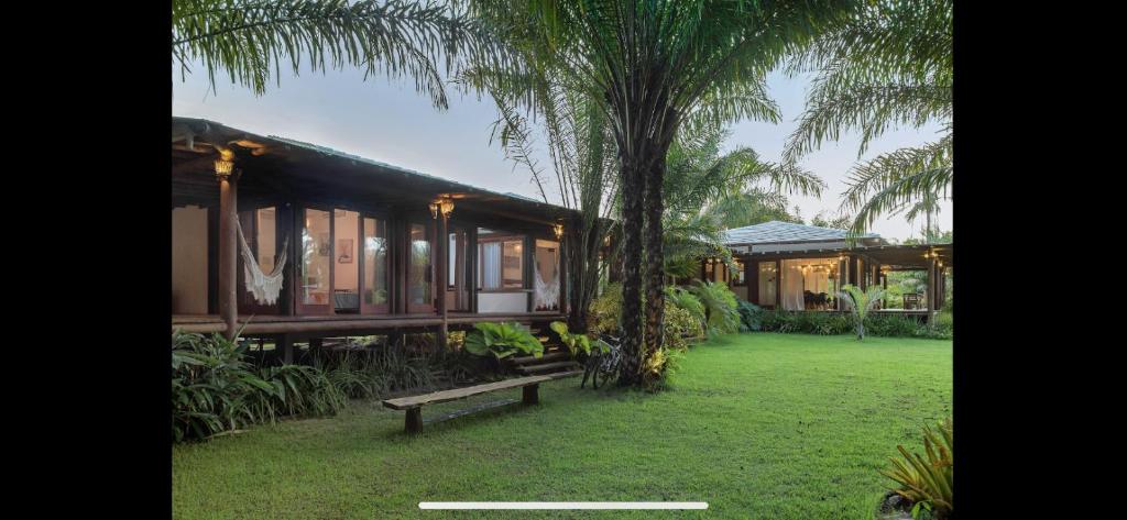a house with a bench next to a palm tree at Paraiso do Dende - Barra Grande - Beira Mar in Barra Grande