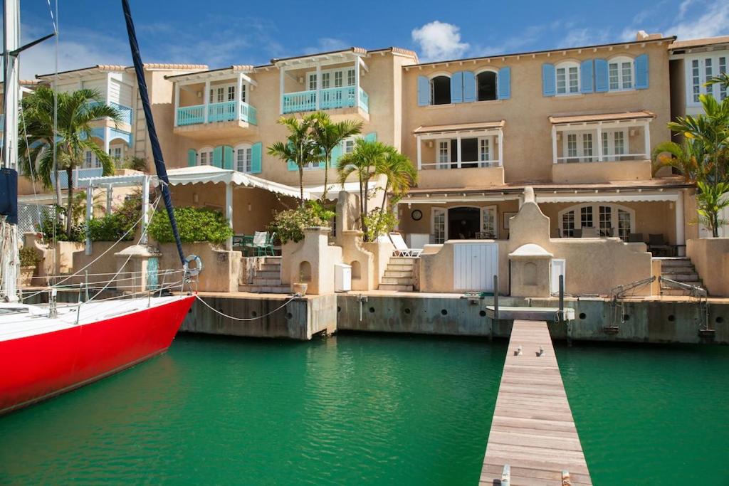 a red boat is docked in front of a building at Spinnaker, #127 Port St. Charles Marina, Speightstown - Waterfront Luxury in Saint Peter