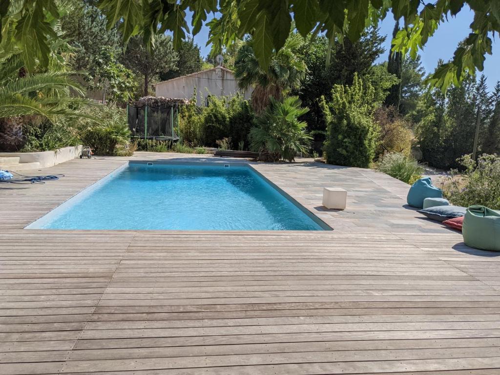 een zwembad in een achtertuin met een houten terras bij Studio indépendant, accès piscine in Le Castellet