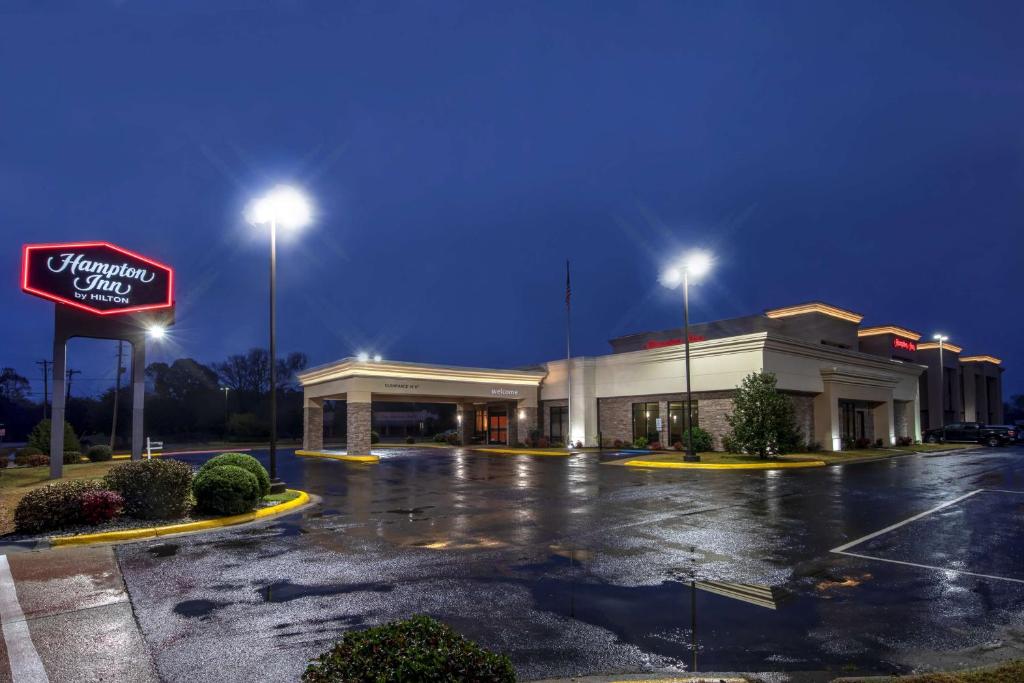 una tienda con un cartel en un estacionamiento por la noche en Hampton Inn Arkadelphia en Arkadelphia