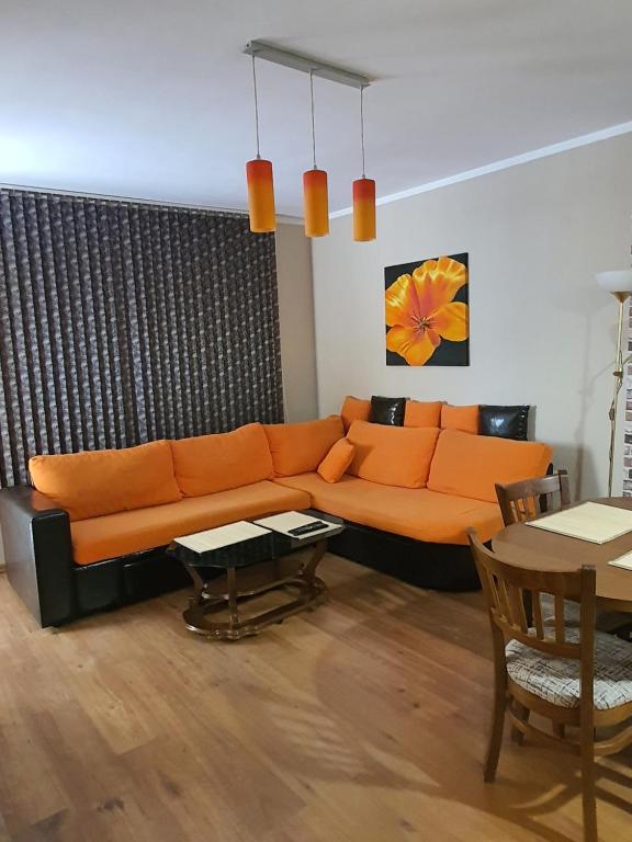 a living room with an orange couch and a table at Нощувки Краткосрочен наем in Plovdiv