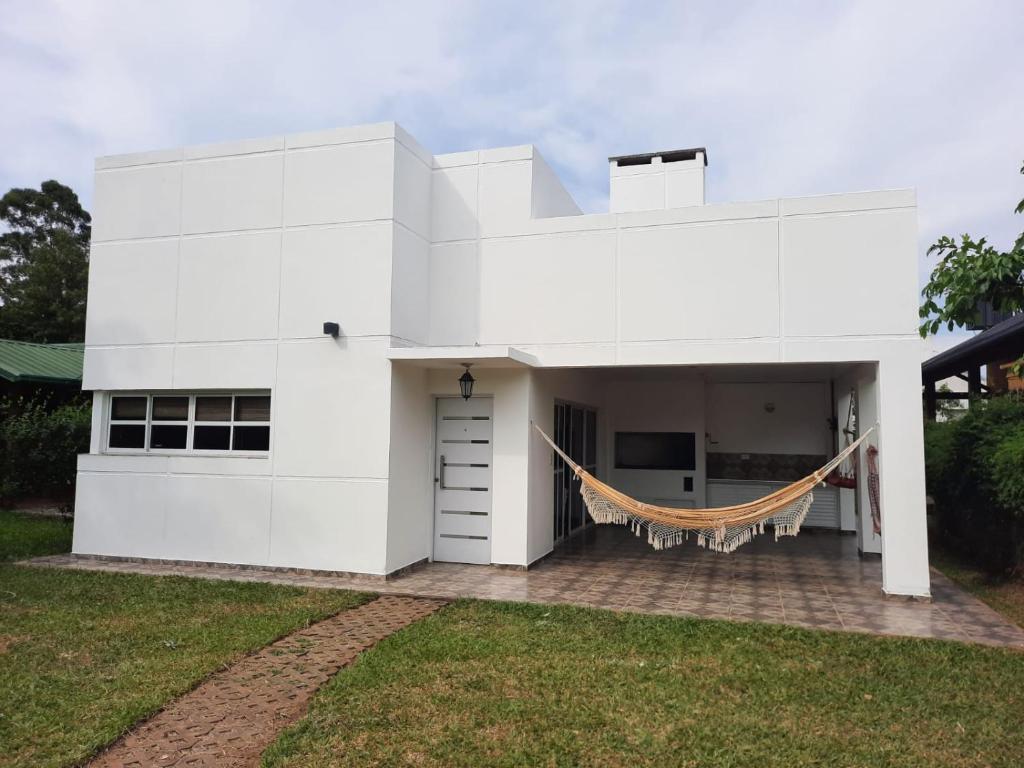 Casa blanca con hamaca en el patio en La Lechuzona- Country Rincon SantaMaria en Ituzaingó
