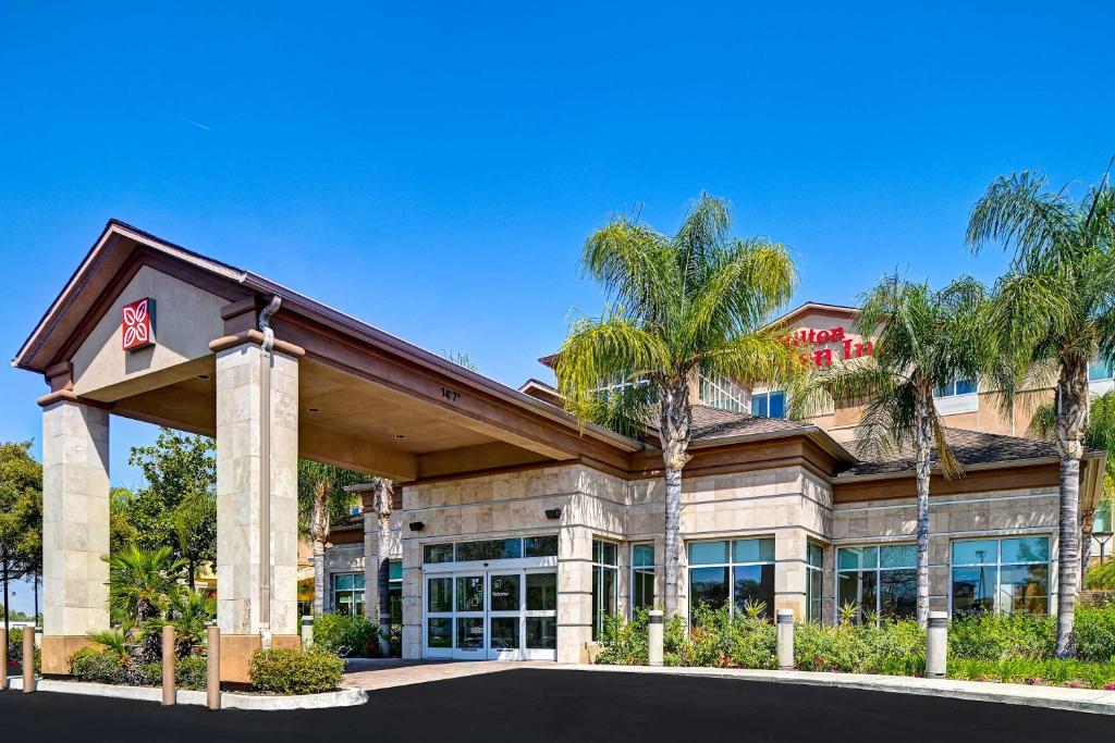 un grand bâtiment avec des palmiers devant lui dans l'établissement Hilton Garden Inn San Bernardino, à San Bernardino