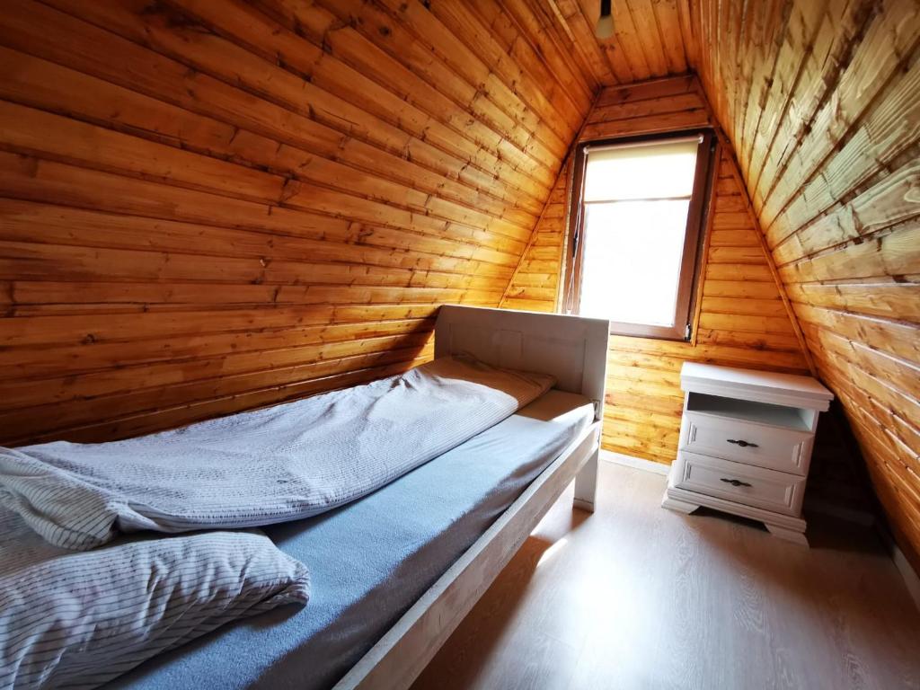 a bed in a wooden room with a window at Livada Becica in Cărbunari