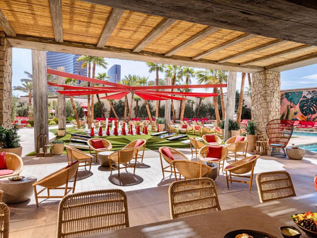 eine Terrasse in einem Resort mit Tischen und Stühlen in der Unterkunft Crockfords Las Vegas, LXR Hotels &amp; Resorts at Resorts World in Las Vegas