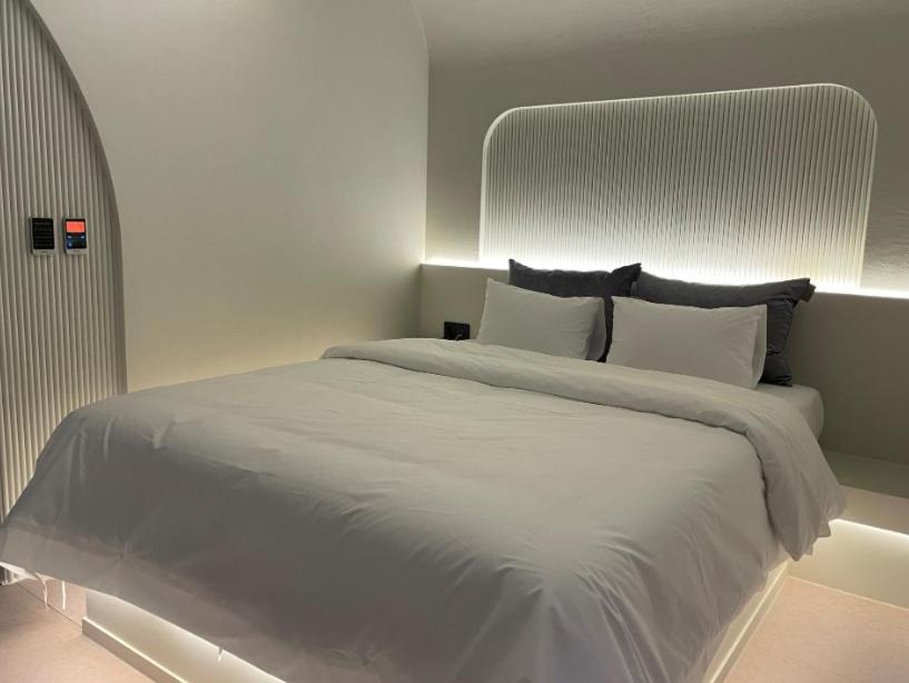 1 dormitorio con 1 cama grande con sábanas y almohadas blancas en D'you Hotel, en Gwangju