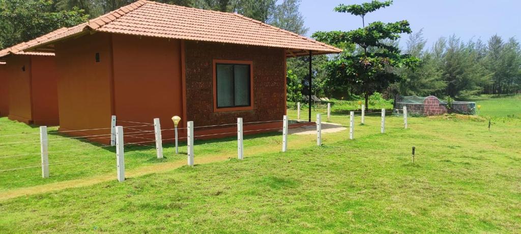 una pequeña casa con una valla delante de ella en 5 Mile Beach Resort, en Kumta