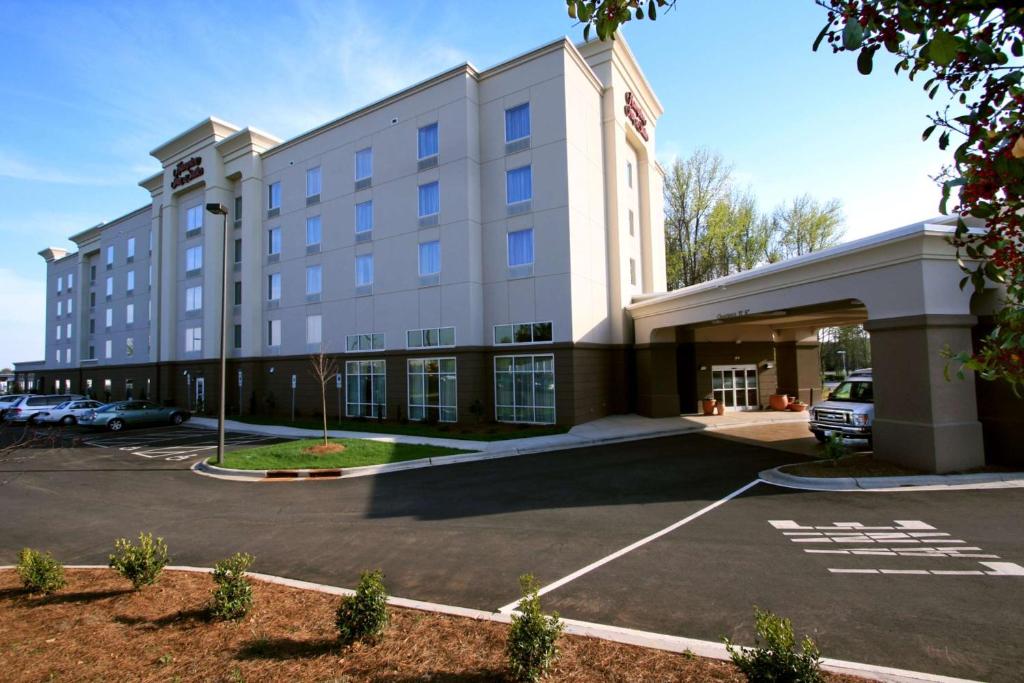 a large white building with a parking lot at Hampton Inn & Suites Charlotte-Airport in Charlotte