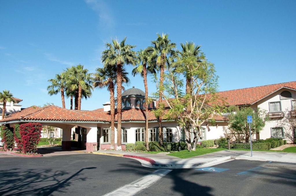 ランチョ・ミラージュにあるHilton Garden Inn Palm Springs/Rancho Mirageの通りの前のヤシの木がある家
