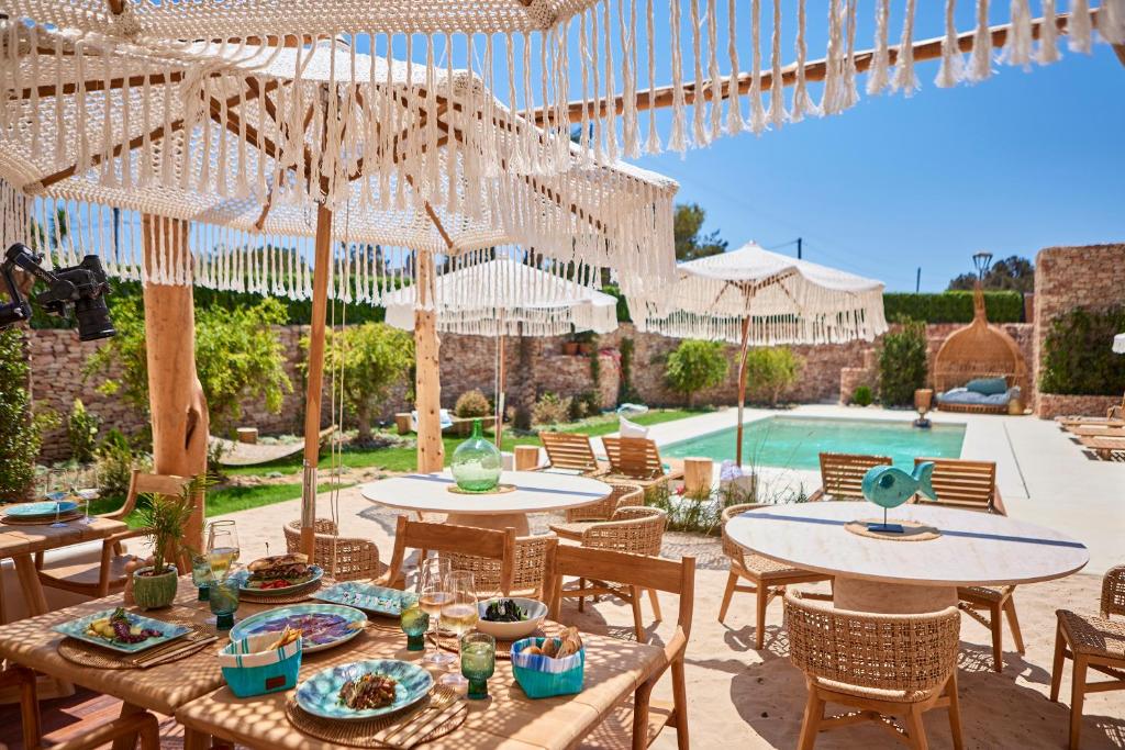 a patio with tables and umbrellas and a pool at Mar Suites Formentera by Universal Beach Hotels in Es Pujols