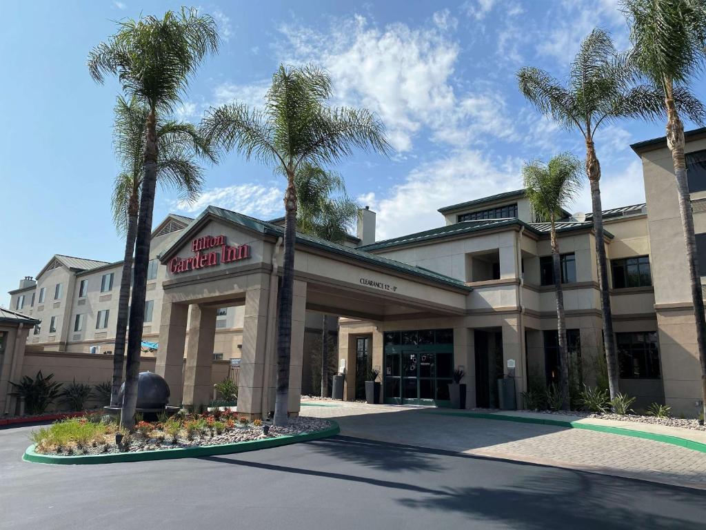 a hotel with palm trees in front of a building at Hilton Garden Inn Montebello / Los Angeles in Montebello