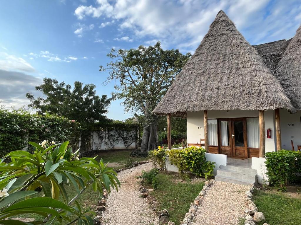 a small white house with a thatched roof at MITI Beach Bungalows in Nungwi