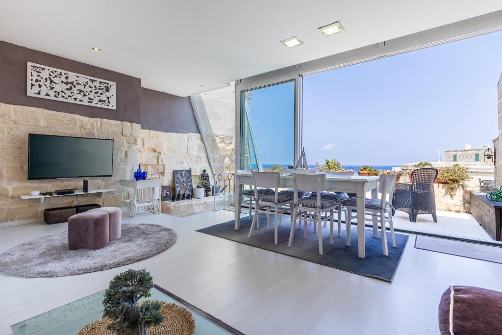 a living room with a table and chairs and a tv at Valletta Bastions Seafront House in Valletta