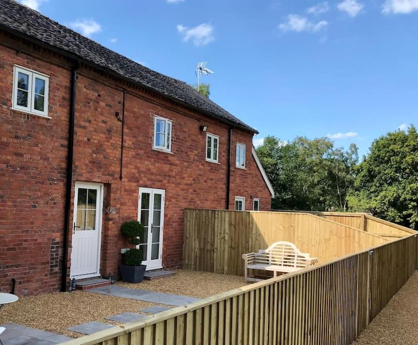 a brick house with a fence and a white bench at The Dairy in Brereton cum Smethwick