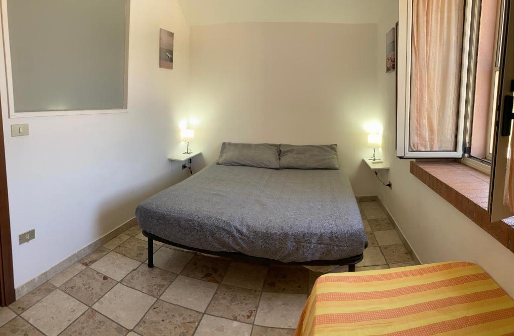 una piccola camera con un letto e due finestre di Casa Gialla - Bilocale indipendente a Soverato Superiore