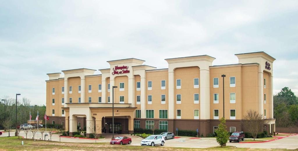 a hotel building with cars parked in a parking lot at Hampton Inn & Suites Palestine in Palestine