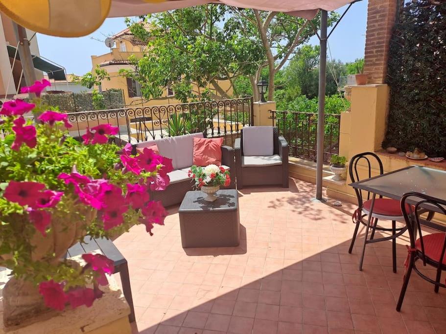un patio con sofá, mesas y flores en La Casetta Di Alfonso, en Santa Marinella
