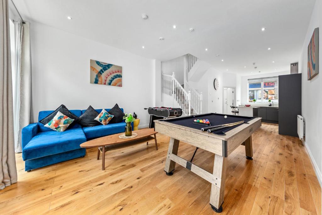 a living room with a blue couch and a ping pong table at Bermondsey Guest House in London