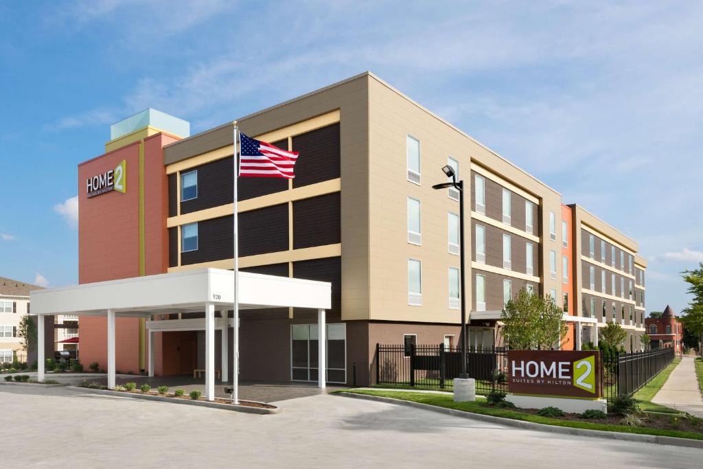 un edificio de oficinas con una bandera americana delante de él en Home2 Suites St. Louis / Forest Park, en Richmond Heights