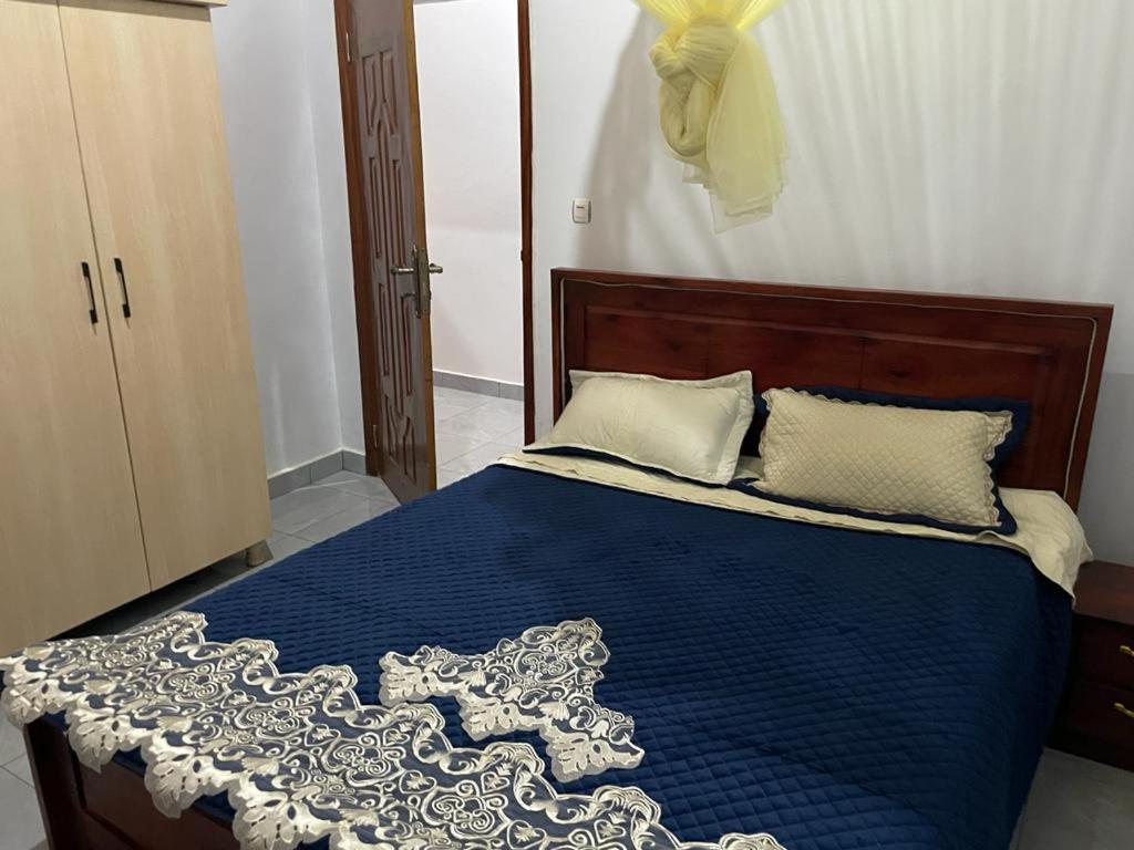 Schlafzimmer mit einem Bett mit blauer Decke in der Unterkunft Best House Kimironko in Kigali