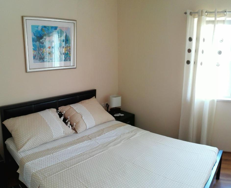 um quarto com uma cama com lençóis brancos e uma janela em Kolombo Apartment em Jadrija