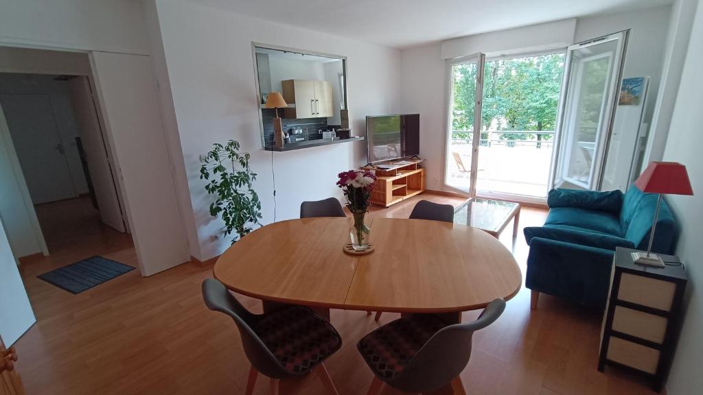 Una sala de estar con una mesa y un sofá azul. en Appartement de 60m2 dans une belle résidence calme, en Neuilly-sur-Marne