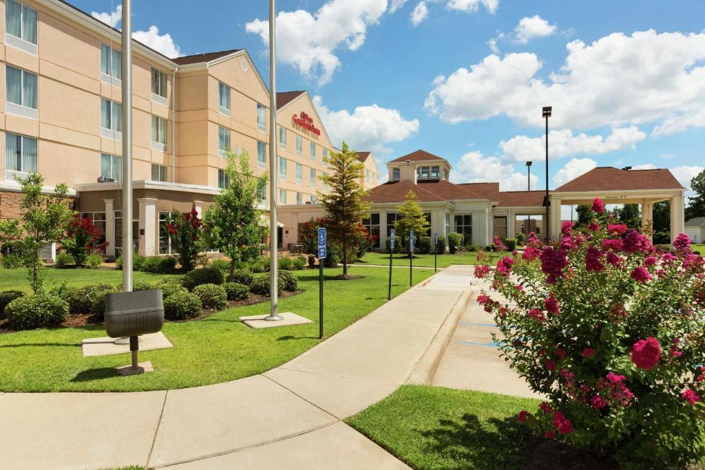 a walkway in front of a hotel with flowers at Hilton Garden Inn Shreveport in Shreveport