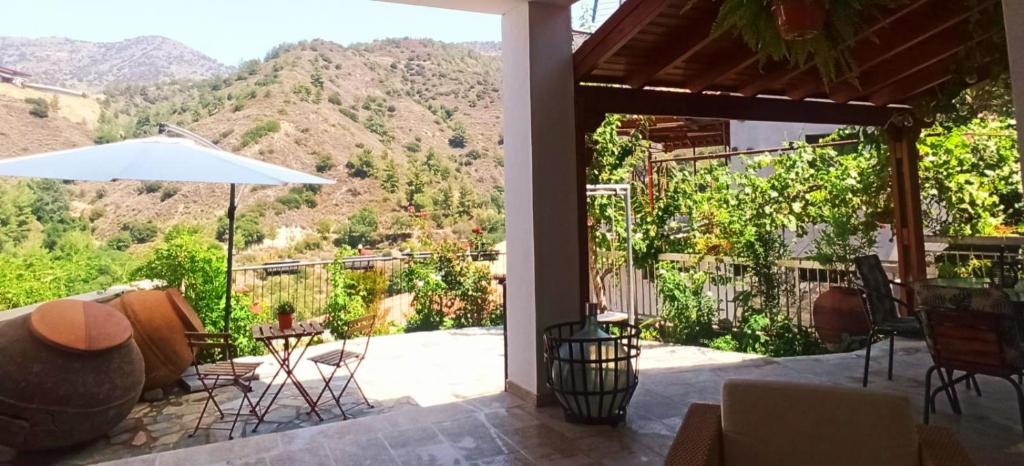 a patio with a table and chairs and an umbrella at BELLE VUE Mountain Home in Kalopanayiotis