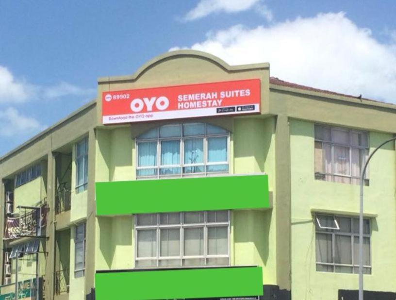 un edificio verde con un letrero rojo. en Semerah Suites Homestay, en Pontian Kecil