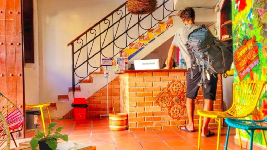 a man is standing in a room with stairs at Fatima Hostel Santa Marta in Santa Marta