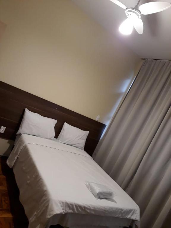 a bed in a room with a ceiling at Hotel Embaixador in Cruzeiro