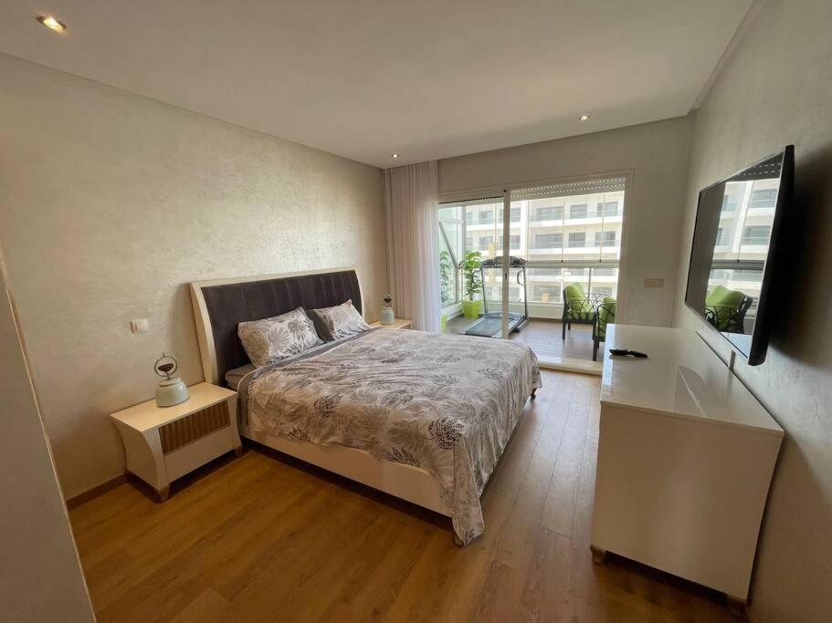 een slaapkamer met een bed en een groot raam bij Appartement de luxe à peninsula in Casablanca