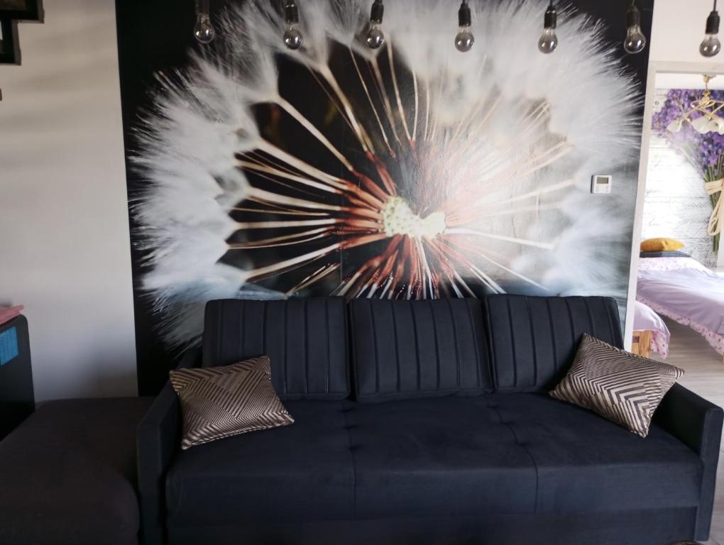 un sofá negro en una habitación con una pared con una pintura en Apartament Klonowa, en Skorochow