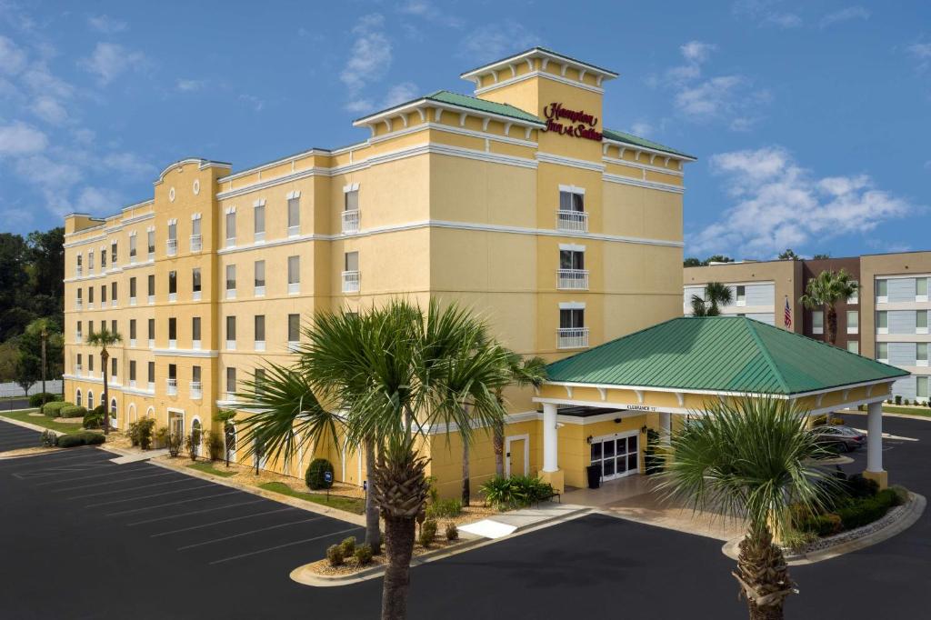 a large yellow building with palm trees in front of it at Hampton Inn & Suites Lake City in Lake City