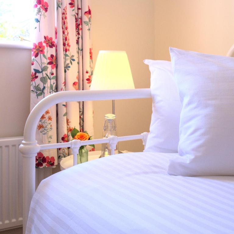Halwell的住宿－Meadowbrook House，卧室配有一张白色床和一张桌子上的台灯