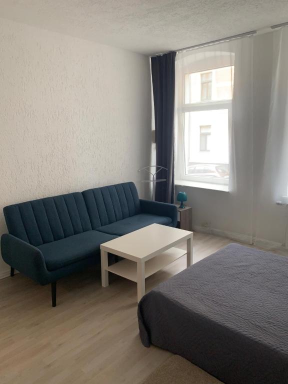 a living room with a blue couch and a table at Am Bahnhof in Zwickau