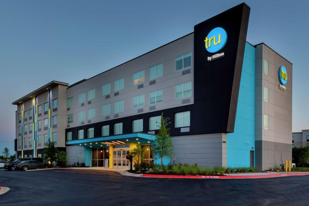 a hotel with a sign on the front of a building at Tru by Hilton Round Rock in Round Rock