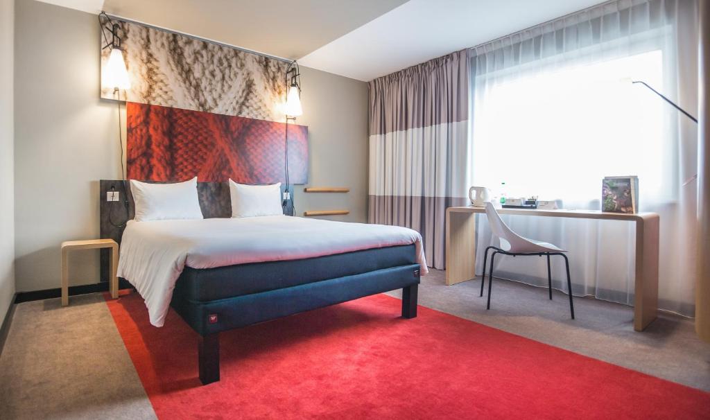 a hotel room with a bed and a red rug at ibis London Stratford in London