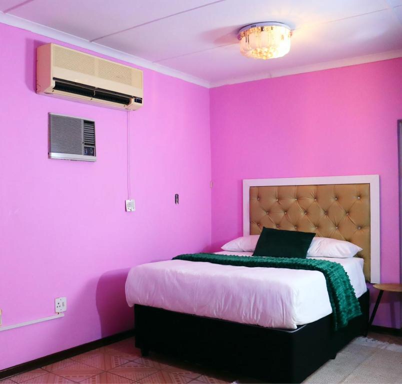 a bedroom with pink walls and a bed in it at Flamingo B&B in Richards Bay