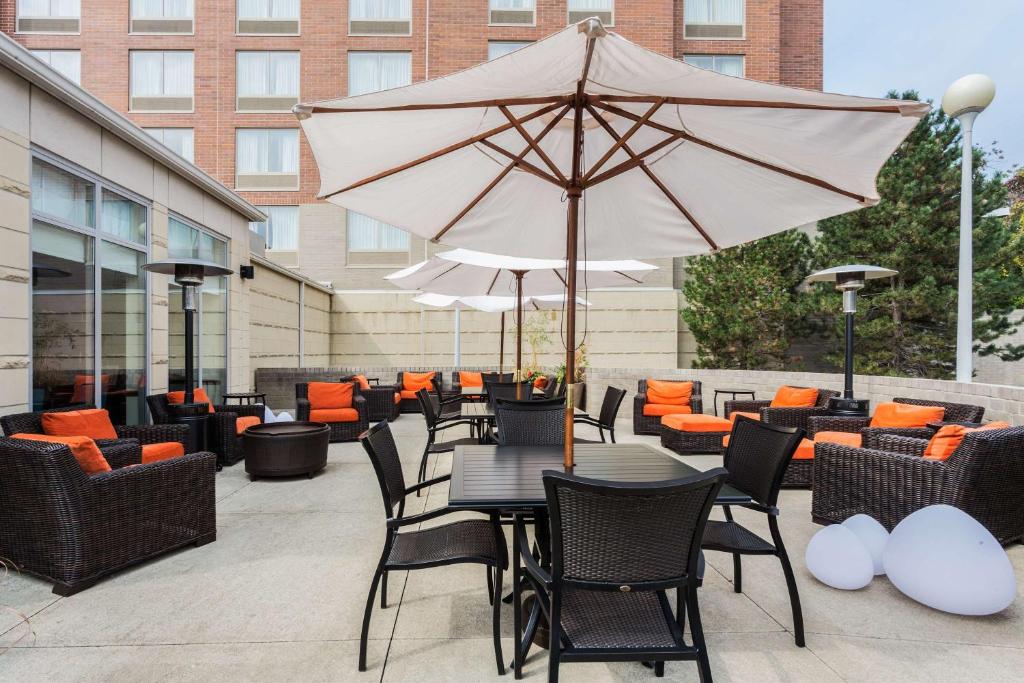 un patio con mesas, sillas y una sombrilla en Hilton Garden Inn Cleveland Airport, en Fairview Park