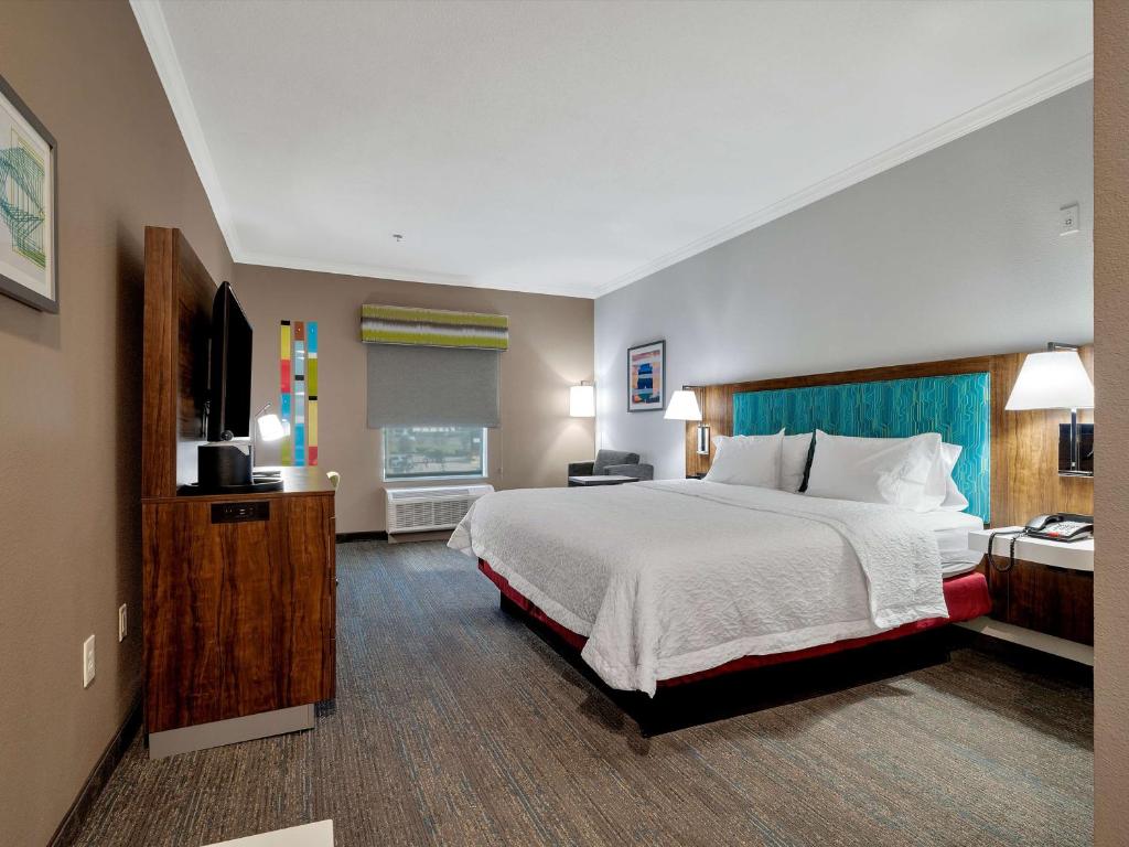 ein Hotelzimmer mit einem Bett und einem Flachbild-TV in der Unterkunft Hampton Inn and Suites Lufkin in Lufkin