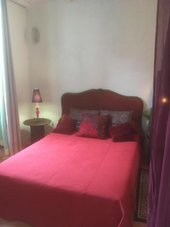 um quarto com uma cama rosa e um cobertor vermelho em Les Arches du Cloître em Corneilla-de-Conflent