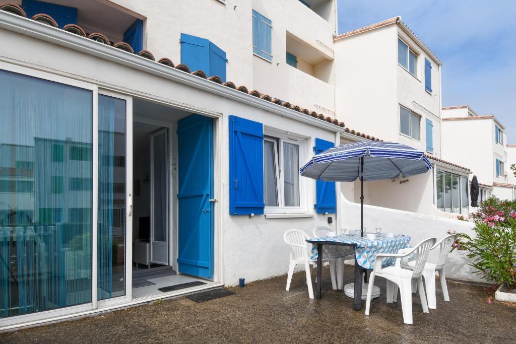 un patio avec une table, des chaises et un parasol dans l'établissement 100m de la plage des Mouettes, appartement pour 4, à Saint-Hilaire-de-Riez