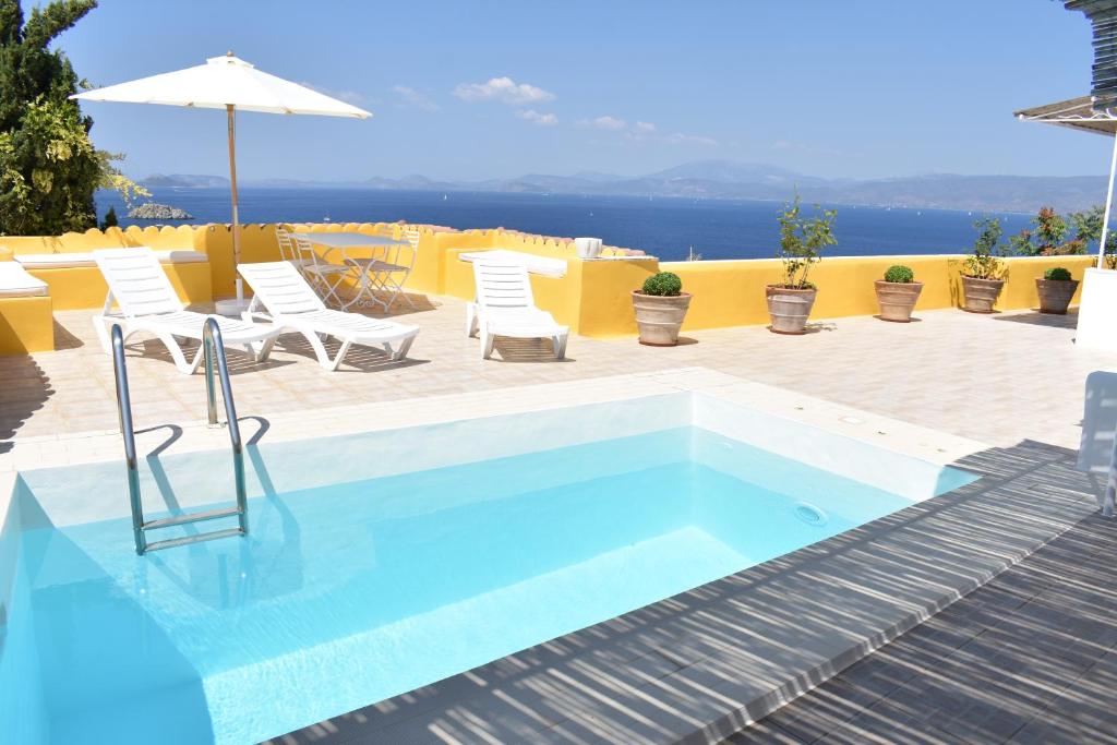 a swimming pool with chairs and an umbrella at Chez Le Goff in Hydra
