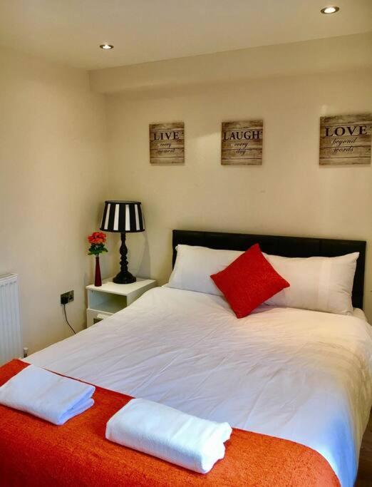 a bedroom with a large bed with red and white pillows at One Bedroom Flat in Central London in London