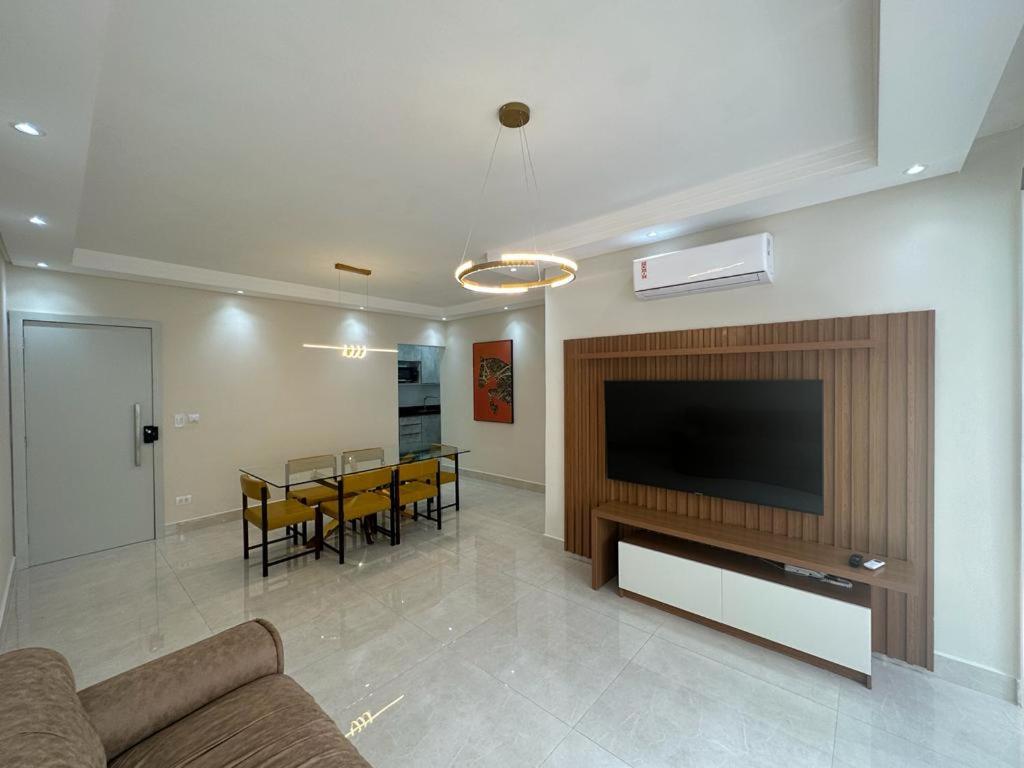 a living room with a television and a dining room at Refúgio Costeiro in Guarujá